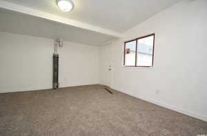 Carpeted spare room with baseboards and lofted ceiling with beams