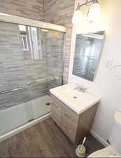 Bathroom featuring vanity, toilet, wood finished floors, and a stall shower