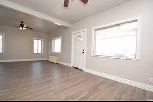 Interior space with a ceiling fan, beam ceiling, baseboards, dark wood-style floors, and radiator