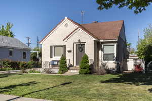 Bungalow-style home featuring a tile roof, a front lawn, and brick siding