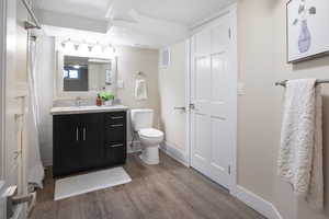 Bathroom featuring vanity, toilet, baseboards, wood finished floors, and visible vents
