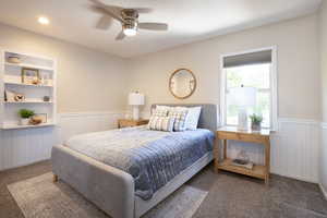 Bedroom with carpet floors, ceiling fan, and a wainscoted wall