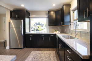 Kitchen with a sink, appliances with stainless steel finishes, tasteful backsplash, and light wood-type flooring