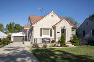 Bungalow with a garage, an outbuilding, a tiled roof, and a front lawn