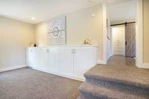 Corridor featuring recessed lighting, baseboards, light colored carpet, and a barn door