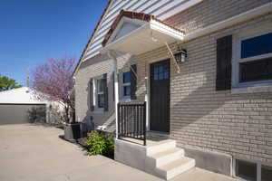 Doorway to property with central AC and brick siding