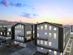 Back of house at dusk with a balcony and stucco siding