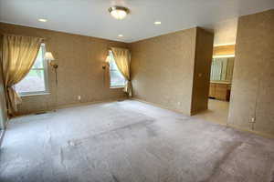 Master bedroom featuring a wealth of natural light, and light carpet