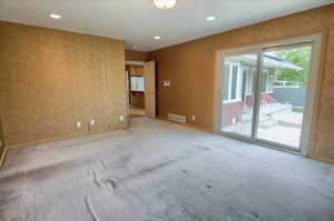 Carpeted master bedroom with recessed lighting, and sliding glass door to patio