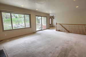 Family room with carpet flooring, large windows, sliding door to patio, and recessed lighting