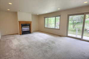 Unfurnished living room with carpet flooring, recessed lighting, baseboards, and a high end fireplace