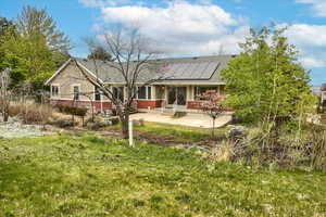 Rear view of house with brick siding, roof mounted solar panels, and shingled roof