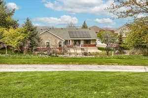 Rear view of property from golf course with a lawn, stucco siding, solar panels, and shingled roof