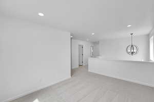 Empty room featuring baseboards, light colored carpet, recessed lighting, and a chandelier