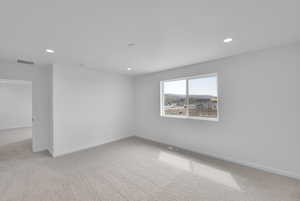 Carpeted empty room with baseboards, recessed lighting, and visible vents