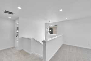 Interior space featuring visible vents, recessed lighting, carpet flooring, a notable chandelier, and an upstairs landing
