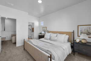 Bedroom with connected bathroom, baseboards, visible vents, and light carpet