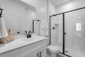 Bathroom featuring vanity, a stall shower, toilet, and wood finished floors