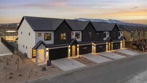 View of front of property with driveway, fence, a mountain view, an attached garage, and stucco siding