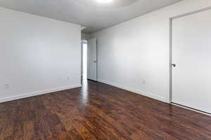 Empty room with baseboards and dark wood-type flooring