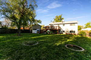 View of yard with fence, a storage unit, a wooden deck, stairway, and an outdoor structure