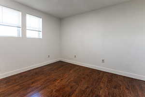 Spare room featuring baseboards and dark wood-type flooring