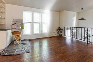 Unfurnished room with visible vents, baseboards, an upstairs landing, and hardwood / wood-style flooring