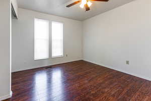 Empty room featuring plenty of natural light, a ceiling fan, wood finished floors, and visible vents