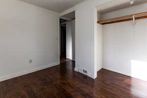 Unfurnished bedroom with visible vents, baseboards, and wood finished floors