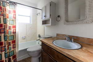 Bathroom with vanity, toilet, and shower / tub combo with curtain