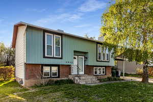 Split foyer home with brick siding and a front yard