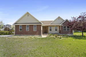 Ranch-style home featuring brick siding, a front lawn, and a porch