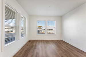 Spare room with baseboards and dark wood-style floors