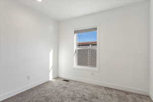 Spare room featuring baseboards, carpet flooring, and visible vents