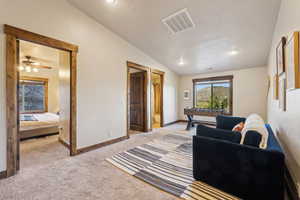 Living room with visible vents, lofted ceiling, light carpet, a textured ceiling, and a ceiling fan