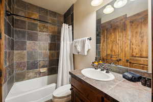 Bathroom with vanity, shower / bath combo, and toilet