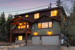 Rustic home featuring stone siding, a garage, aphalt driveway, stucco siding, and a balcony