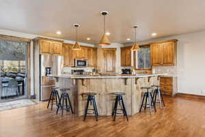 Kitchen featuring a breakfast bar area, stainless steel appliances, wood finished floors, and backsplash