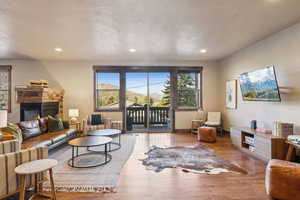 Living area with recessed lighting, a stone fireplace, a healthy amount of sunlight, and wood finished floors