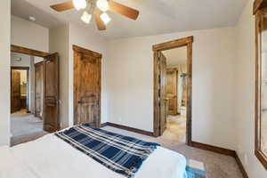 Bedroom with a ceiling fan, baseboards, light colored carpet, and ensuite bathroom