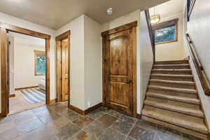 Stairs featuring baseboards, a healthy amount of sunlight, and stone tile flooring