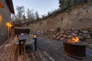 Wooden terrace with outdoor dining space, a hot tub, and an outdoor fire pit