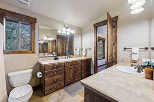Bathroom featuring visible vents, vanity, toilet, tile patterned floors, and vaulted ceiling