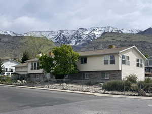 Exterior space with brick siding, a fenced front yard, a mountain view, and a chimney