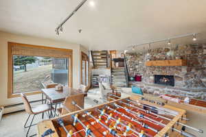 Playroom with carpet flooring, a stone fireplace, and track lighting