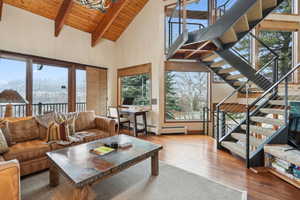 Living room featuring stairway, wood ceiling, beamed ceiling, high vaulted ceiling, and hardwood / wood-style flooring