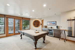 Recreation room featuring a bar, light colored carpet, beverage cooler, and recessed lighting