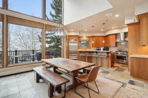 Dining area featuring a high ceiling, recessed lighting, an inviting chandelier, and stone finish flooring