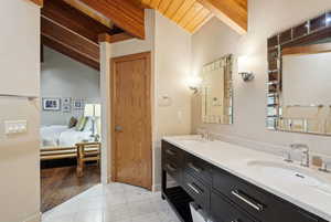 Ensuite bathroom featuring a sink, double vanity, tile patterned flooring, and wood ceiling