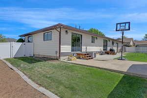 Rear view of house featuring a patio, a gate, a fenced backyard, and a yard